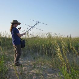 a woman outdoors with potable ham radio antenna