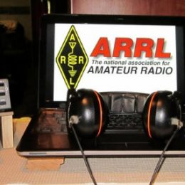 a small ham radio, headphones, and laptop