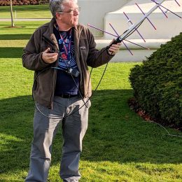 a man holding a portable ham radio antenna outside