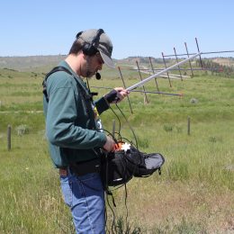 man holding a radio antenna out in a field