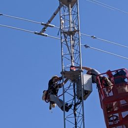 workers installing an antenna rotator atop a tall radio tower