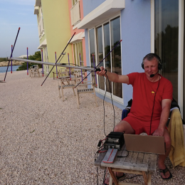man holding small radio antenna near a beach resort