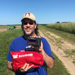 man holding qrp radio in farm field