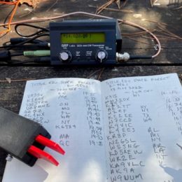 ham radio, keyer paddles, and logbook on outdoor table