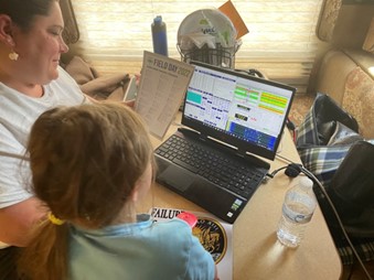 Child participating in Field Day, sitting at a laptop