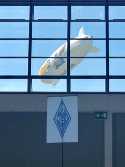 blimp being pictured through a window of a convention center