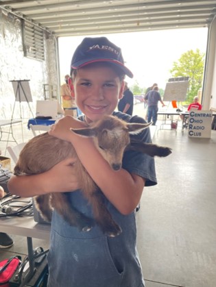 young boy holding a baby goat at fair