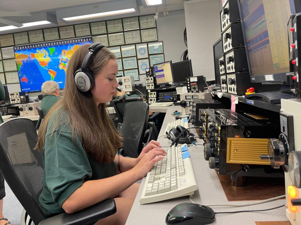 young lady typing on keyboard at a large ham radio station