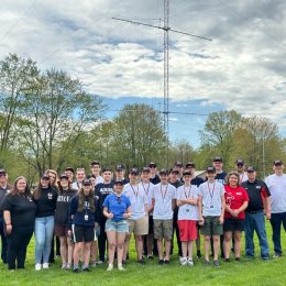 group of teenagers near a large ham radio antenna