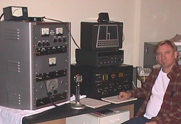 a man sitting at a vintage ham radio station