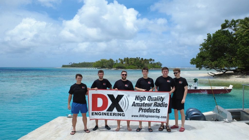 group of ham radio operators with banner on beach