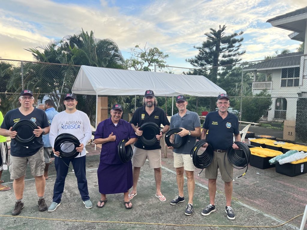 group of men outside holding coaxial cable