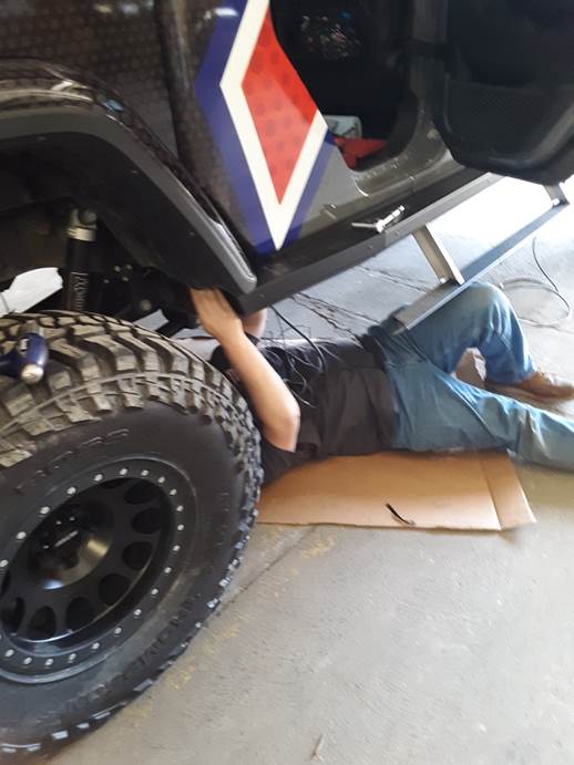 man installing wires underneath a Jeep