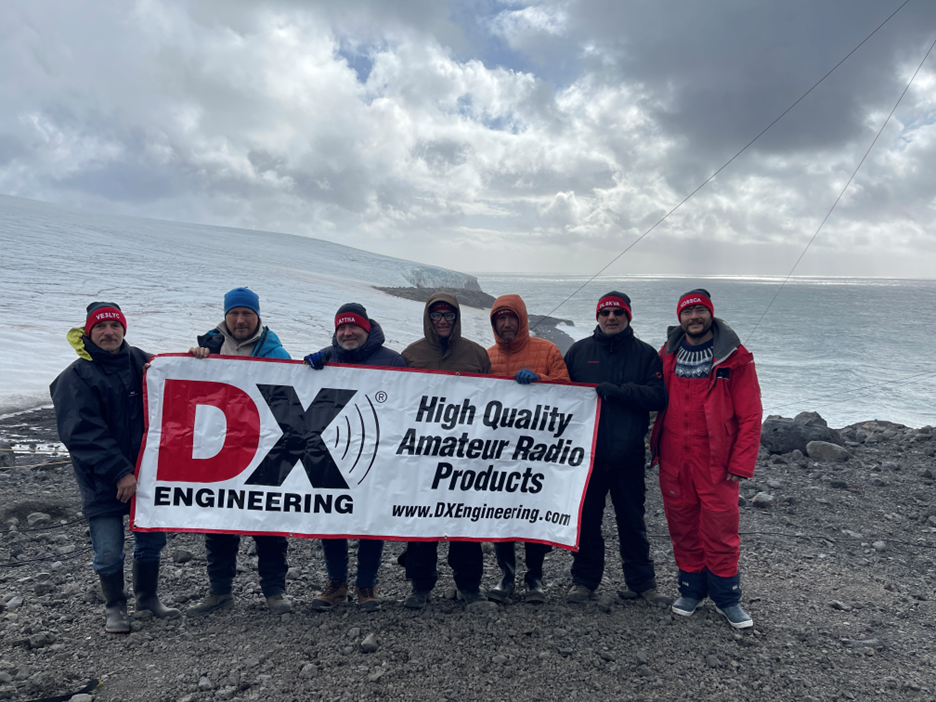 Men on a remote beach holding a large banner