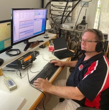 man at controls of ham radio destop base station