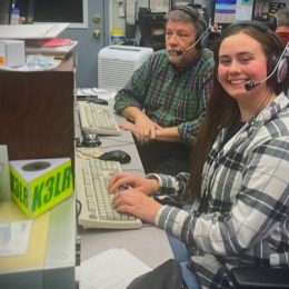 2 operators sitting at a ham radio station desk