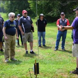 man speaking to group of ham radio operators outside