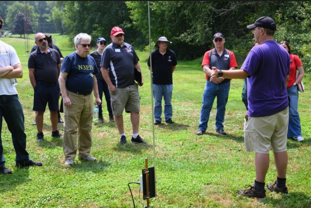 man speaking to group of ham radio operators outside