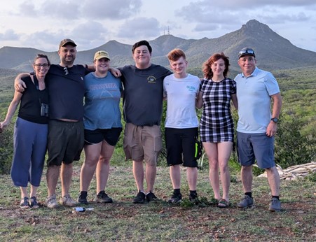 a group of people posing in front of a mountain range