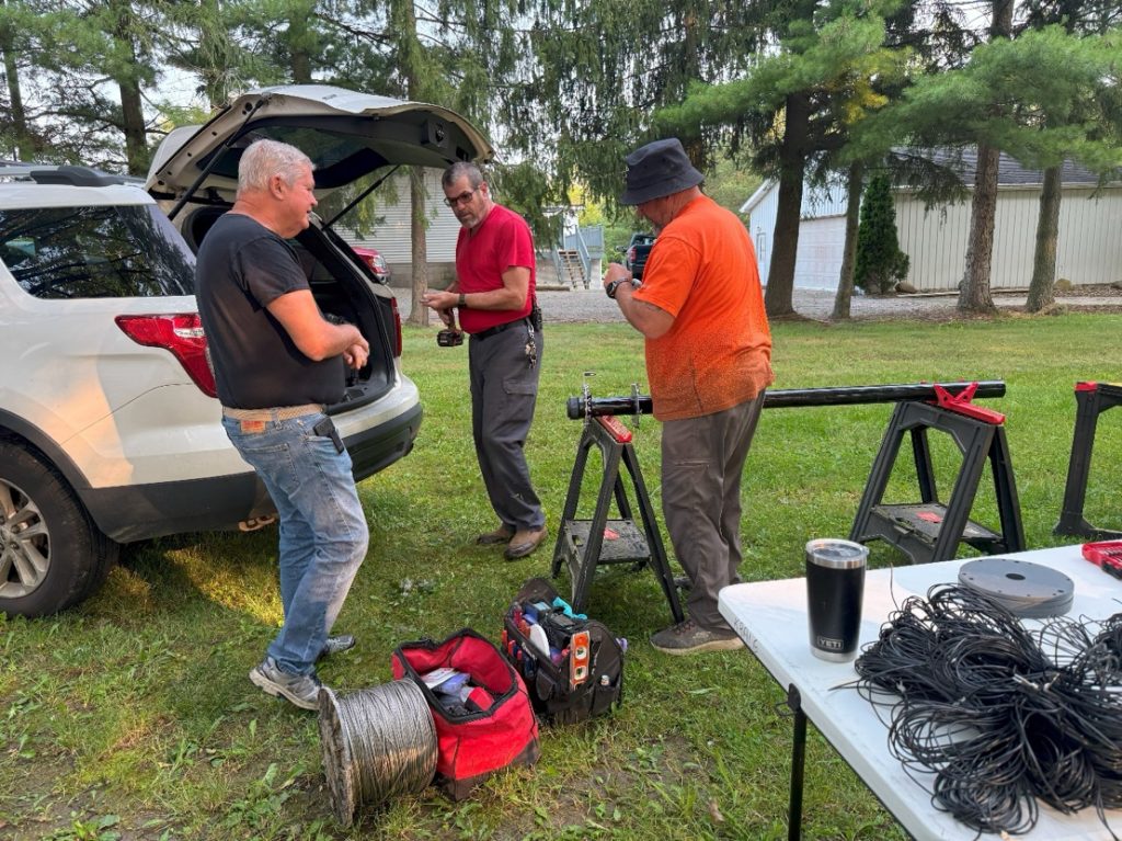 men assembling an antenna mast outside