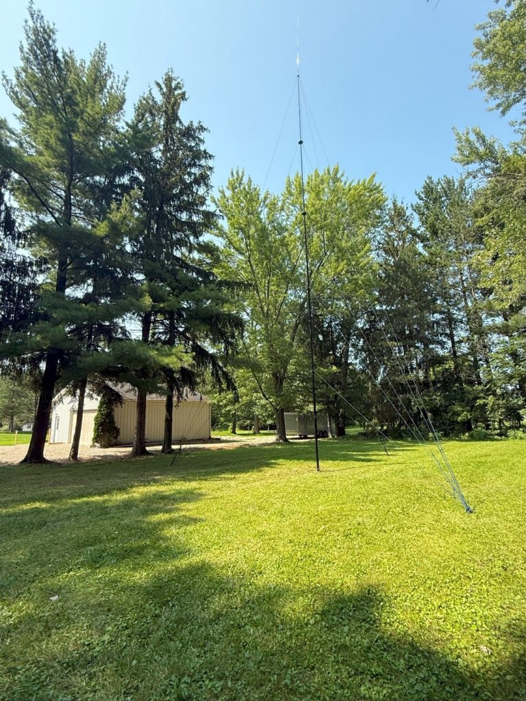 vertical antenna mast erected in a grass lot
