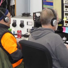 two ham radio operators sitting at controls