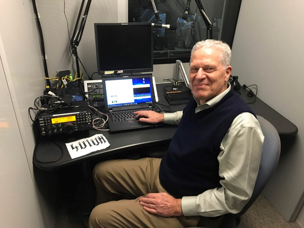 man sitting at controls of ham radio station